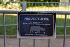 Germany, Saxony-Anhalt, Magdeburg, entrance to the zoo with the sign "Keep your distance", 1.5 meters or half a black rhinoceros. Germany, Saxony-Anhalt, Magdeburg, entrance to the zoo with the sign "Keep your distance", 1.5 meters or half a black rhinoceros.
